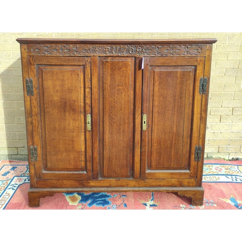 425 - Antique oak hall cupboard, the frieze bearing date 1709 over a pair of panelled doors, on bracket fe... 