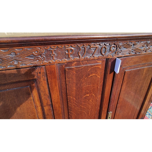 425 - Antique oak hall cupboard, the frieze bearing date 1709 over a pair of panelled doors, on bracket fe... 