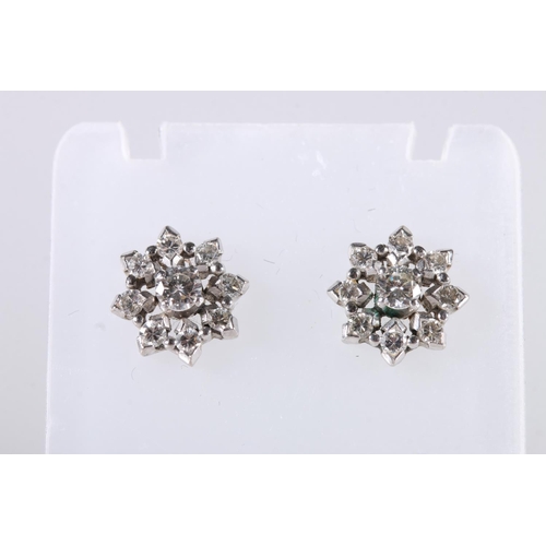 199 - Pair of unhallmarked white metal earrings of flower head form set with diamonds, the central diamond... 