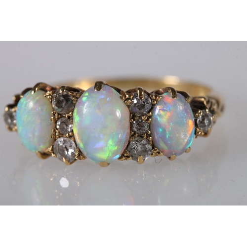 214 - Unhallmarked yellow metal gem set ring, the three oval opals surrounded by eight diamond, ring size ... 