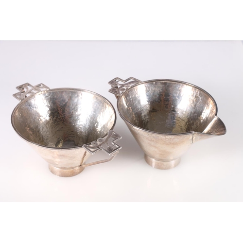 91 - Arts & Craft hammered white metal sugar bowl and cream jug with pierced floral design handles, u... 