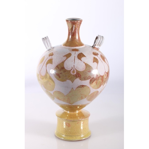 437 - Lustre glazed terracotta amphora style vase with two ring handles raised on circular base, in the ma... 