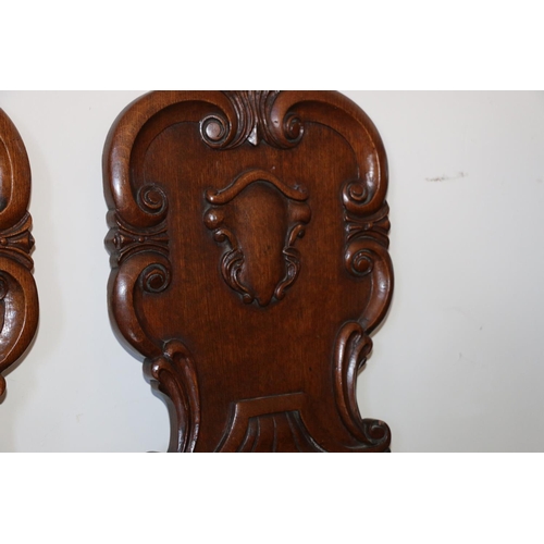 495 - Pair of Victorian carved oak hall chairs, the shield backs with scroll border, raised on turned supp... 