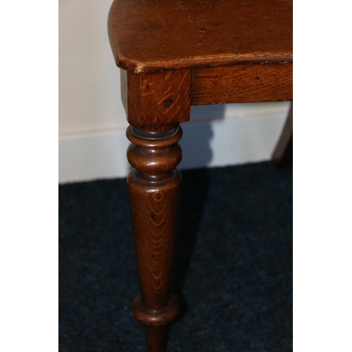 495 - Pair of Victorian carved oak hall chairs, the shield backs with scroll border, raised on turned supp... 