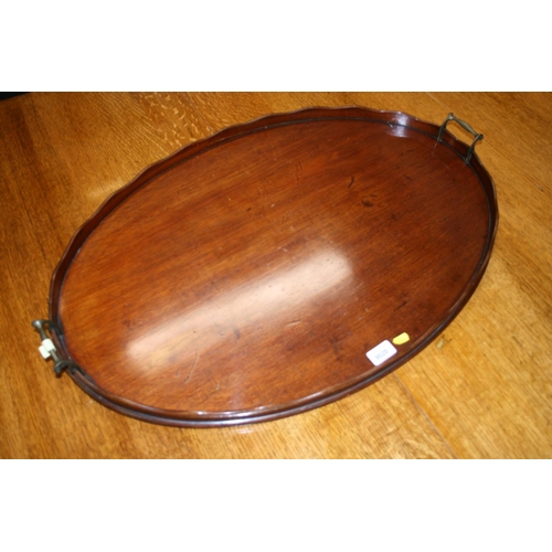 514 - Antique mahogany oval tray with serpentine gallery and twin metal handles, 78cm wide.