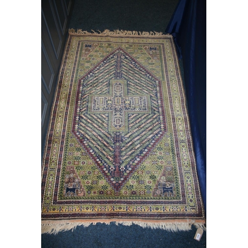 537 - Persian style green ground rug, the midnight blue field with large central lozenge having cross to t... 