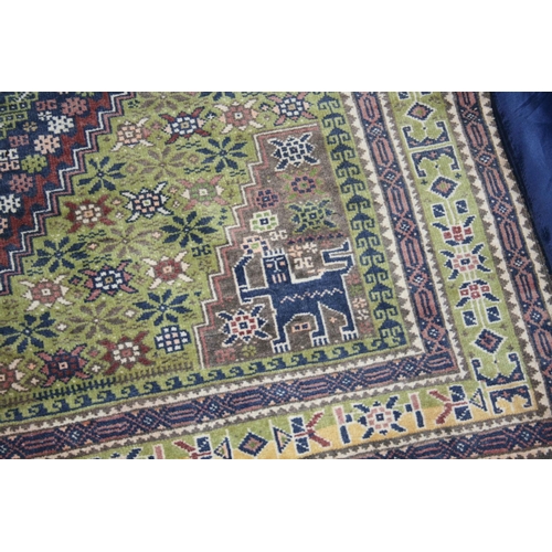 537 - Persian style green ground rug, the midnight blue field with large central lozenge having cross to t... 