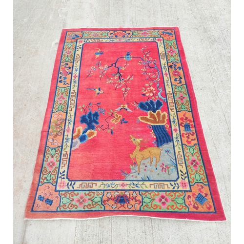 228 - Chinese red ground rug, a deer in the corner below a blossom tree with birds, decorative cream guard... 