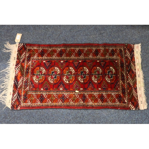 545 - Turkoman mat sized rug, the red field with six guls, kelim style brocade ends, fringed, 100cm x 53cm... 