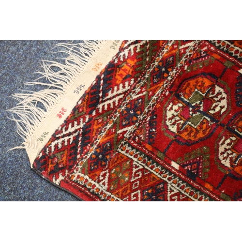 545 - Turkoman mat sized rug, the red field with six guls, kelim style brocade ends, fringed, 100cm x 53cm... 