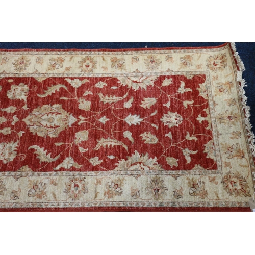 551 - Ziegler style runner, the red field with scrolling floral design framed by cream border, fringed end... 