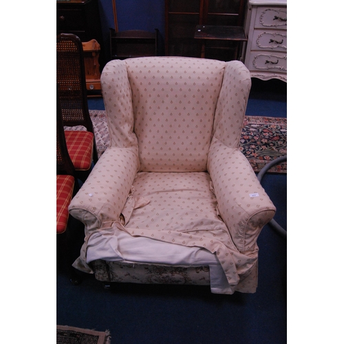 477 - Antique upholstered wing armchair on later brass castors.