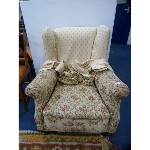 447 - Antique upholstered wing armchair on later brass castors.