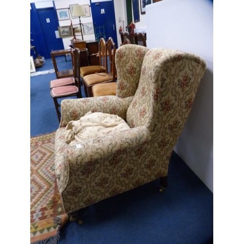 447 - Antique upholstered wing armchair on later brass castors.