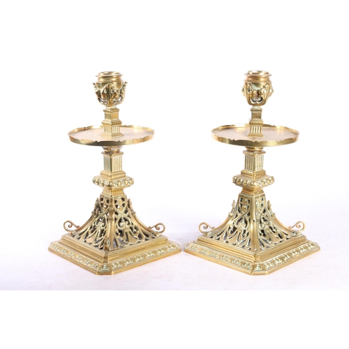 67 - Pair of pierced brass candlesticks with circular galleries platform drip trays raised on square base... 