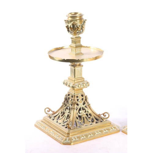 67 - Pair of pierced brass candlesticks with circular galleries platform drip trays raised on square base... 