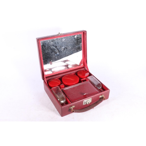 85 - Art Deco style red leather hinge top vanity case, the lid with mirror inset and red plastic topped t... 