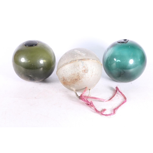 92 - Two green glass fishing floats and a metal float. (3)