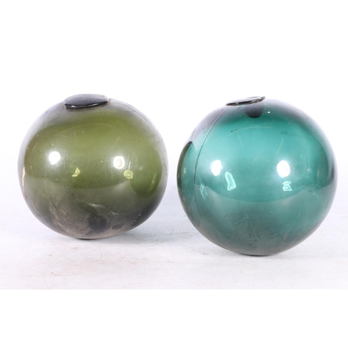 92 - Two green glass fishing floats and a metal float. (3)