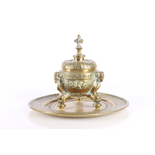 155 - Indian brass inkwell raised on ram mask and dolphin supports, 19cm diameter.