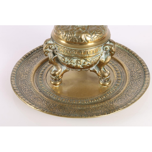 155 - Indian brass inkwell raised on ram mask and dolphin supports, 19cm diameter.