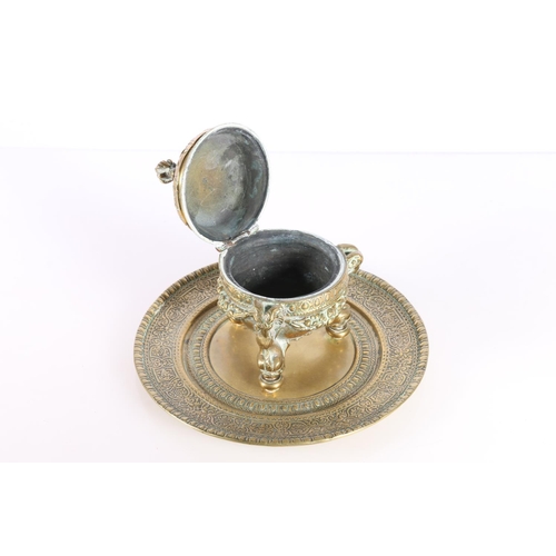 155 - Indian brass inkwell raised on ram mask and dolphin supports, 19cm diameter.