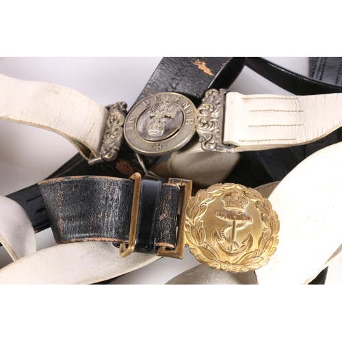 396 - Naval gilded brass belt buckle on black leather belt and a white metal In Defence belt buckle on whi... 