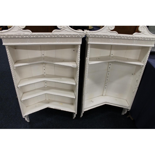 296 - Pair of cream painted wall mounted bookcases with scroll pediments, 106cm tall.