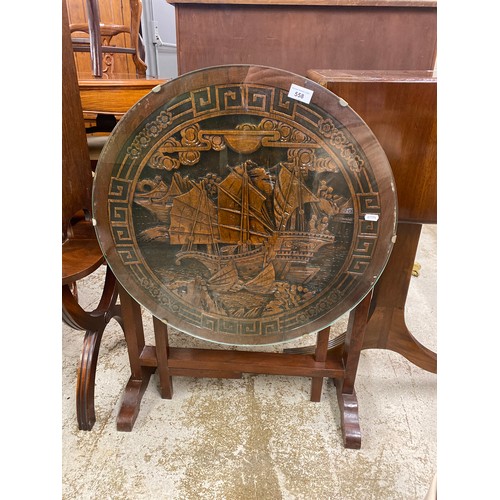 558 - Fold down occasional table, top in Oriental style with ship in relief and glass top, 61 cm in diamet... 