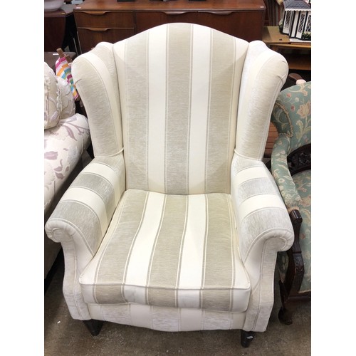 570A - Cream wing back fireside chair.