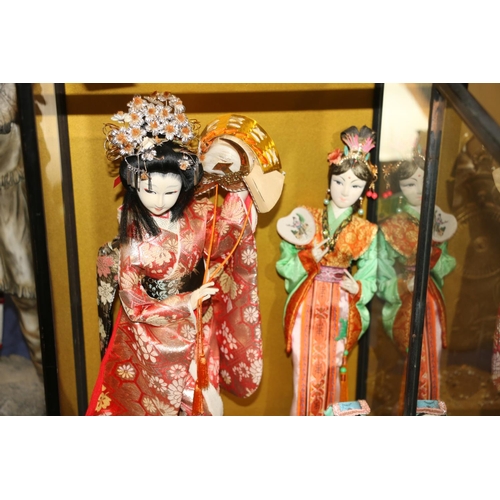 156 - Japanese felt faced doll of a geisha in traditional dress and other similar dolls, in display case 5... 