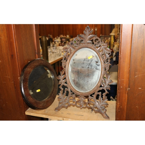 244 - Black Forest carved mirror on easel back, the frame with grapes and leaves, and a small oval wall mi... 