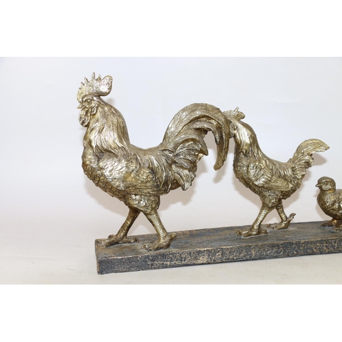 274 - Gilt cast resin model group of evolving cockerels from egg to chicken, 57cm long.