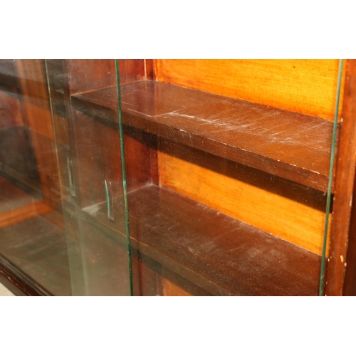 673 - Mahogany effect three shelf wall display cabinet with sliding glazed doors, 122cm wide.