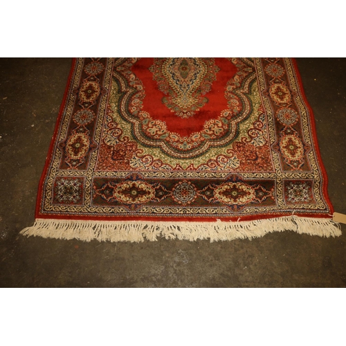 714 - Persian rug, rust red ground with repeating floral scrolls, 190cm x 140cm.