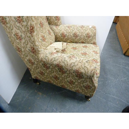 287 - Antique upholstered wing armchair on later brass castors.