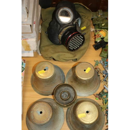 205 - Four cast brass bells, a Trench Art cigarette ashtray made from a 1918 artillery shell, and a gas ma... 