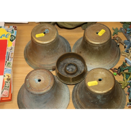 205 - Four cast brass bells, a Trench Art cigarette ashtray made from a 1918 artillery shell, and a gas ma... 