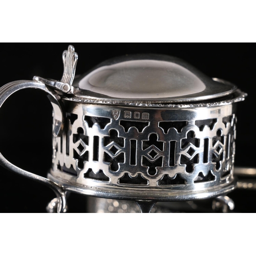 572 - George V silver mustard pot with hinged lid, C scroll handle, with interior blue glass liner on thre... 