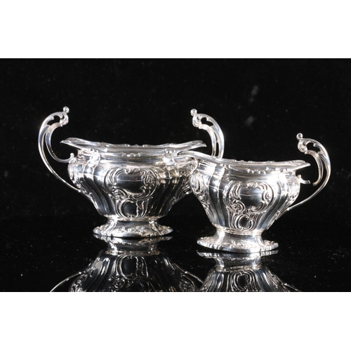 574 - Victorian silver cream jug and matching sugar, scrolled handles with rococo embossed design to the b... 