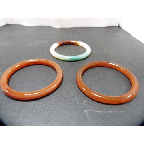 235 - Three Oriental-style hardstone bangles.