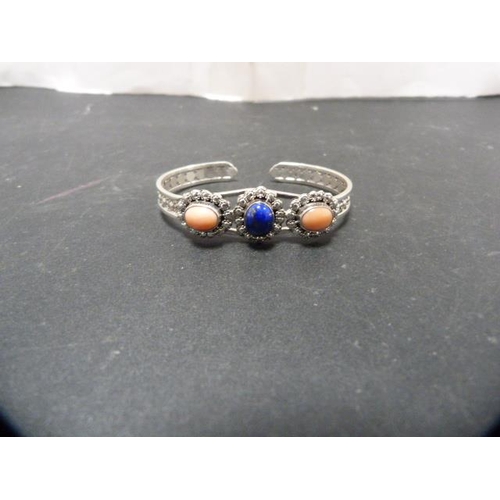 241 - Two silver bangles, one set with lapis-style and coral-style stones, 44.4g gross, and another bangle... 