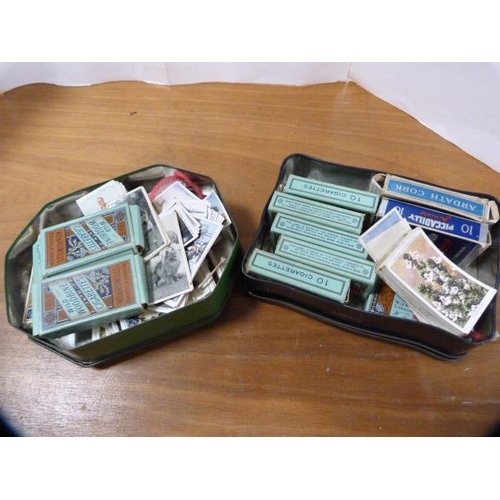 71 - Two tins containing a collection of cigarette cards to include some folders and loose examples.