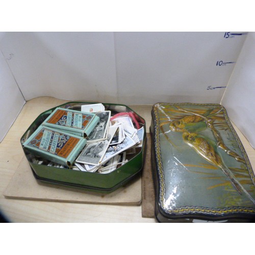 71 - Two tins containing a collection of cigarette cards to include some folders and loose examples.