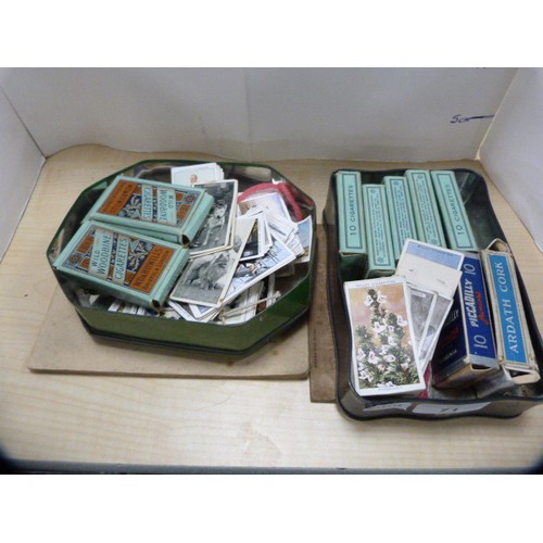 71 - Two tins containing a collection of cigarette cards to include some folders and loose examples.