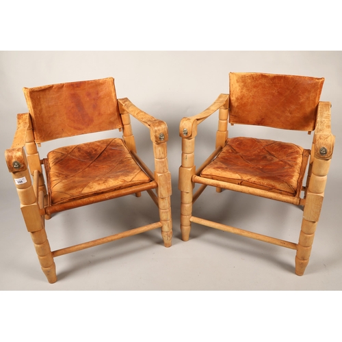 598 - Pair of 20th century Indian easy chairs of teak construction with stretched leather back and arm res... 