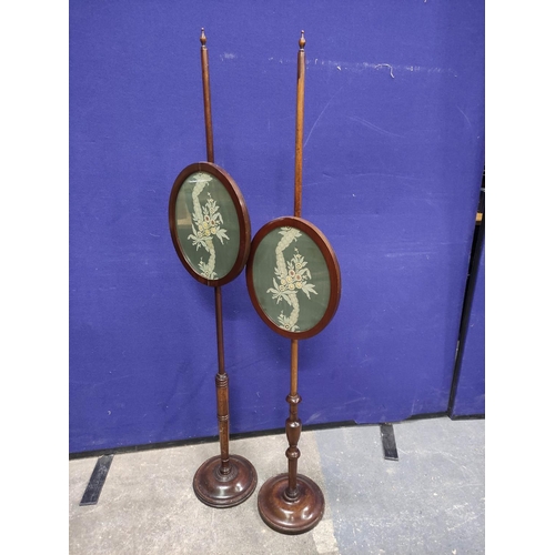 455 - Two 19th century pole screens with turned columns and finials with oval fabric panels on turned base... 