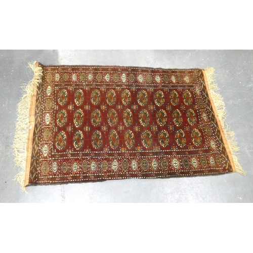 435 - Tekke hand knotted rug with nine rows of three geometric motifs on red ground, 190cm x 125cm