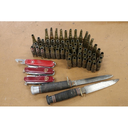 137 - Three Swiss Army style multi-tool knives, two other knives and a band of used shell cartridges.