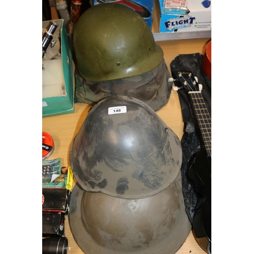 148 - Three military helmets to include one with camouflage cover and fibreglass insert.